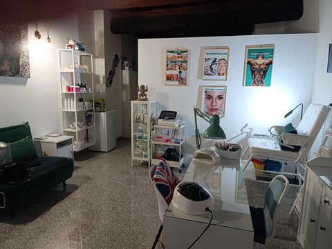 Modern salon interior with styling stations, white shelving, framed artwork on walls, and professional beauty equipment